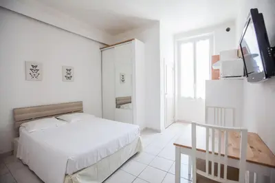 a white bedroom with a bed and a tv at Appartements Foch in Cannes