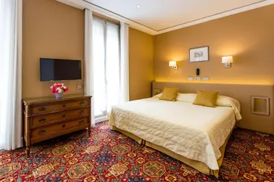 a bedroom with a bed and a television and a dresser at Hotel Splendid in Cannes
