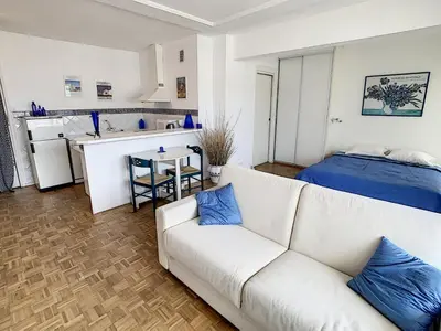 a living room with a white couch and a kitchen at Ibis Studio 5380 in Cannes