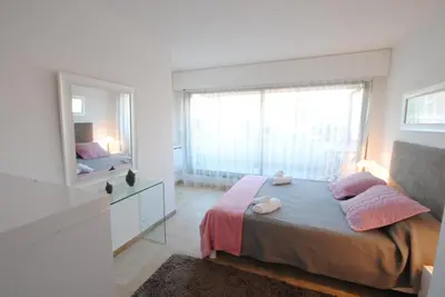 a white bedroom with a bed and a mirror at Résidence Gray d'Albion 2P LIU5376 in Cannes