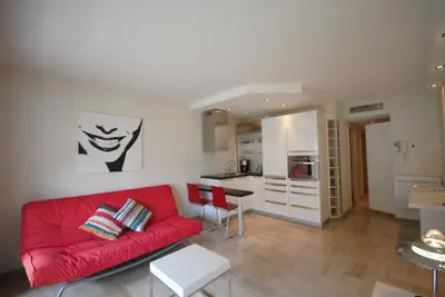 a living room with a red couch and a kitchen at Résidence Gray d'Albion 2P NAP558 in Cannes
