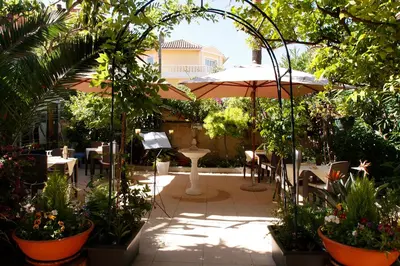 a patio with an umbrella and tables and chairs at Hotel Chalet De L'isere in Cannes