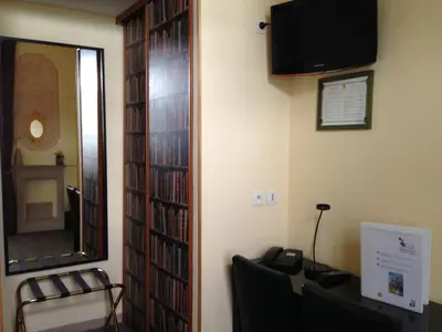 a room with a mirror and a book shelf with dvds at Hotel Chalet De L'isere in Cannes