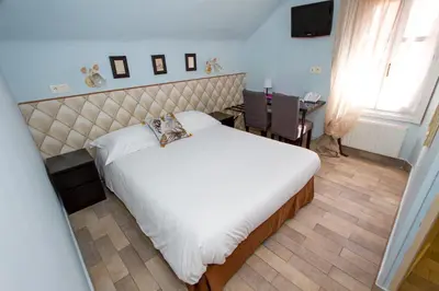 a bedroom with a large white bed and a desk at Hotel Chalet De L'isere in Cannes