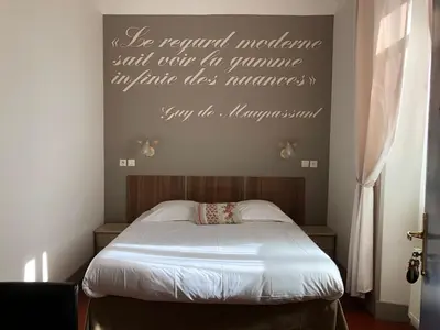a bedroom with a bed with a sign on the wall at Hotel Chalet De L'isere in Cannes