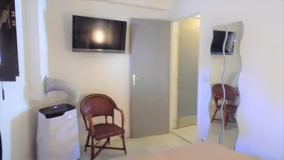 a room with two chairs and a television on the wall at CANNES plage 2mn/45m2/vue mer/inernet/clim/parking privé in Cannes