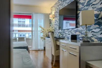 a kitchen with a sink and a desk with a mirror at Hotel Le Fouquet's in Cannes