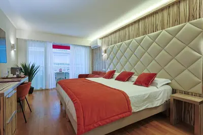 a bedroom with a large bed with a large headboard at Hotel Le Fouquet's in Cannes