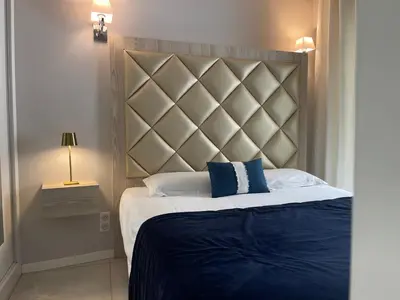 a bedroom with a bed with a large headboard at Hotel Le Fouquet's in Cannes