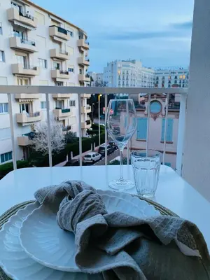 a plate and wine glasses on a table on a balcony at Studio Cannes la Croisette in Cannes