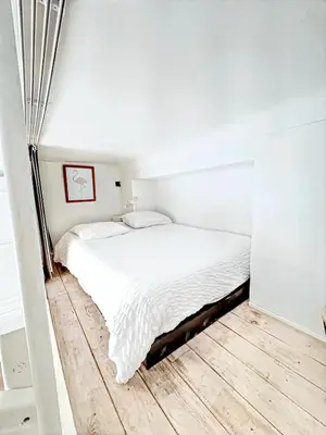 a bedroom with a white bed and a wooden floor at Mini Duplex 50m du Vieux Port in Cannes