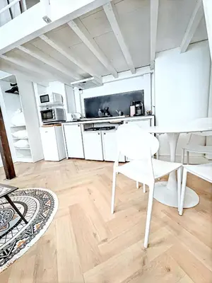 a kitchen with white cabinets and a table and chairs at Mini Duplex 50m du Vieux Port in Cannes