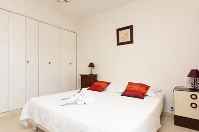 a white bedroom with a white bed with red pillows at Palais Royal YourHostHelper in Cannes