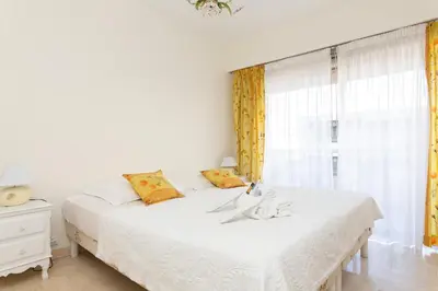 a white bedroom with two beds and a window at Palais Royal YourHostHelper in Cannes