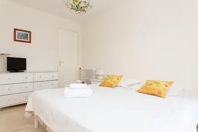 a white bedroom with a white bed and a tv at Palais Royal YourHostHelper in Cannes