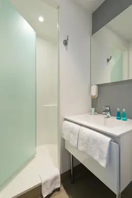 a white bathroom with a sink and a shower at ibis budget Cannes Centre Ville in Cannes