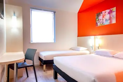 a room with two beds and a desk and a window at ibis budget Cannes Centre Ville in Cannes