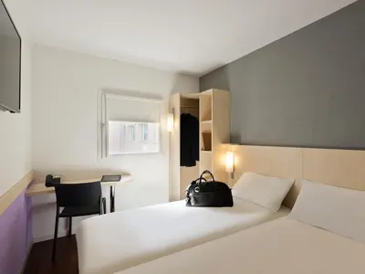 a bedroom with a white bed with a black bag on it at ibis budget Cannes Centre Ville in Cannes