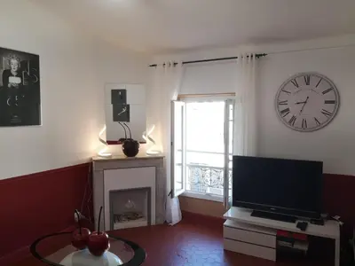 a living room with a clock on the wall and a television at 5 min to sea and Palais des Festivals in Cannes