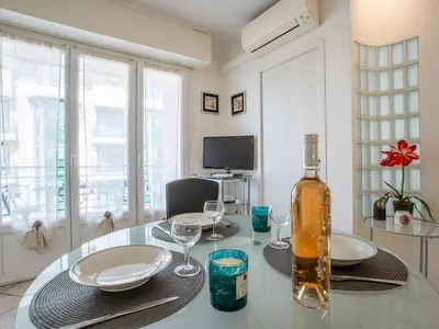 a dining room table with a bottle of wine on it at Apartment Le Cheverny by Interhome in Cannes