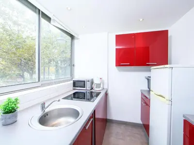 a kitchen with red cabinets and a sink and a window at Apartment Le Corsaire-5 by Interhome in Cannes