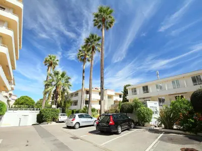 two cars parked in a parking lot with palm trees at Apartment Le Marlyne 1 by Interhome in Cannes