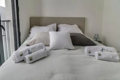 a white bed with four pillows on it at IMMOGROOM- Modern - Elegant - Close to the beach -AC in Cannes