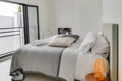 a white bedroom with a bed with a window at IMMOGROOM- Modern - Elegant - Close to the beach -AC in Cannes