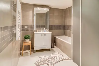 a bathroom with a sink and a tub and a mirror at IMMOGROOM- Modern - Elegant - Close to the beach -AC in Cannes