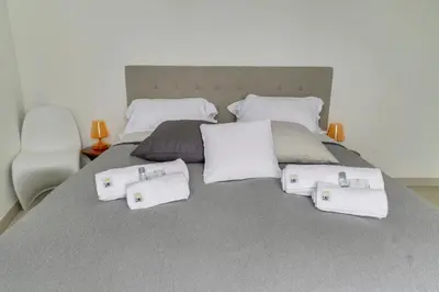 a bed with white towels and pillows on it at IMMOGROOM- Modern - Elegant - Close to the beach -AC in Cannes