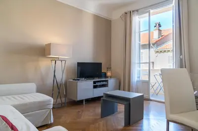 a living room with a couch and a tv and a window at Spacious one bedroom - great location! in Cannes