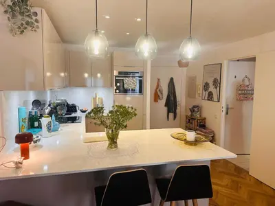 a kitchen with a island with chairs and lights at Lovely one bedroom apartment with balcony & wifi just minutes walk from Palais and Cannes beaches 109 in Cannes