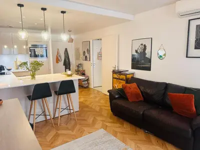 a living room with a black leather couch and a kitchen at Lovely one bedroom apartment with balcony & wifi just minutes walk from Palais and Cannes beaches 109 in Cannes