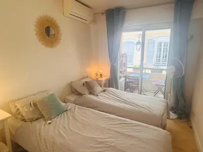 a bedroom with two beds and a balcony with a table at Lovely one bedroom apartment with balcony & wifi just minutes walk from Palais and Cannes beaches 109 in Cannes