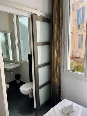 a bathroom with a toilet and a sink and a window at Chanteclair in Cannes