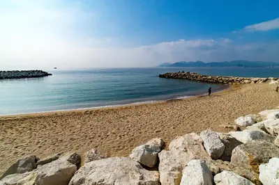 a person walking on a beach next to the ocean at 3 pièces- Vieux port- Terrasse - Parking Possible in Cannes