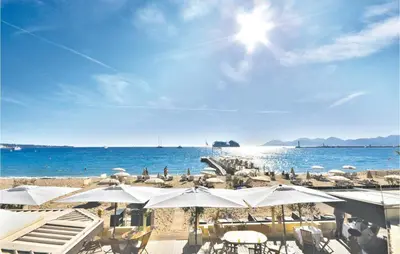 a beach with white umbrellas and the ocean at 1 Bedroom Lovely Apartment In Cannes in Cannes