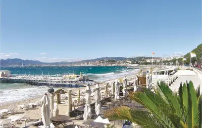 a beach with white umbrellas and chairs and a pier at 1 Bedroom Lovely Apartment In Cannes in Cannes