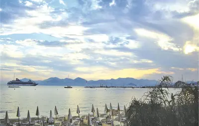 a beach with chairs and a cruise ship in the water at 1 Bedroom Lovely Apartment In Cannes in Cannes