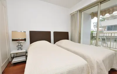 a white bedroom with two beds and a window at 1 Bedroom Lovely Apartment In Cannes in Cannes