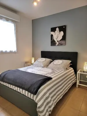 a bedroom with a bed with striped sheets and a window at Bristol Park - parking - 5mn walk from Palais des Festivals in Cannes