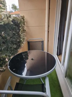 a table and chair on a balcony with a window at Bristol Park - parking - 5mn walk from Palais des Festivals in Cannes