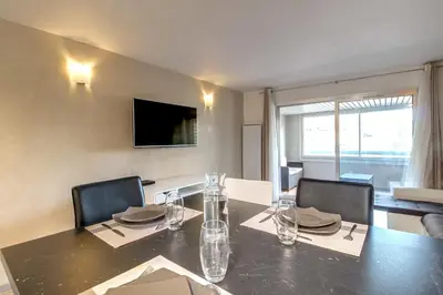 a dining room with a table with chairs and a television at IMMOGROOM- Renovated - Wifi - Close to everything in Cannes