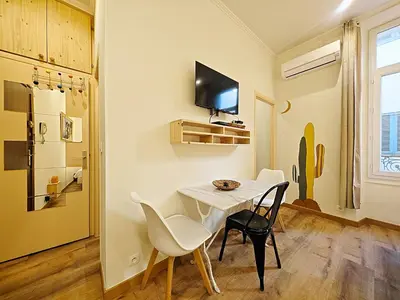 a dining room with a table and chairs and a tv at Viva Riviera - 19 rue des Frères Pradignac in Cannes