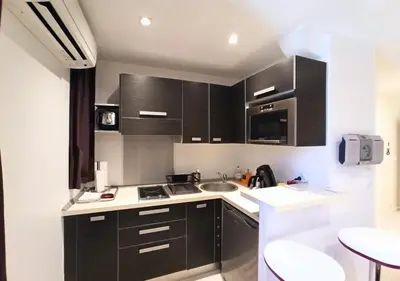 a kitchen with black cabinets and a sink at Viva Riviera - 19 rue des Frères Pradignac in Cannes