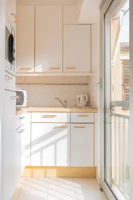 a kitchen with white cabinets and a window at Studio à deux pas du Palais des Festivals in Cannes