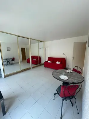 a living room with a table and a red couch at Studio à deux pas du Palais des Festivals in Cannes