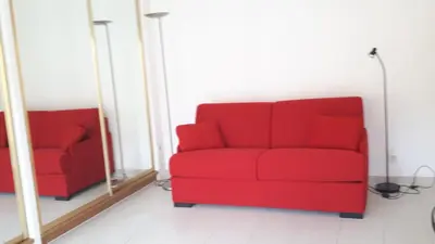 a red couch in front of a mirror at Studio à deux pas du Palais des Festivals in Cannes