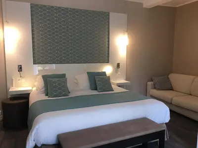 a hotel room with a large bed and a couch at Hotel Molière in Cannes