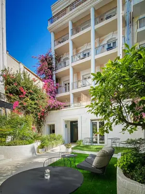 a patio with a table and chairs in front of a building at Hotel Molière in Cannes